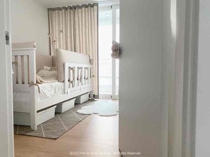 White and beige toned kids' room featuring a baby bed and bear-shaped rug with a cozy atmosphere