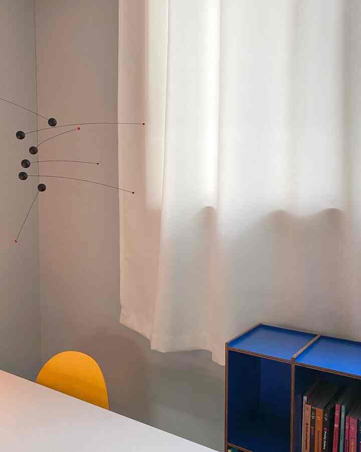 White and blue toned bedroom space featuring a yellow chair and mobile decoration with a simple atmosphere