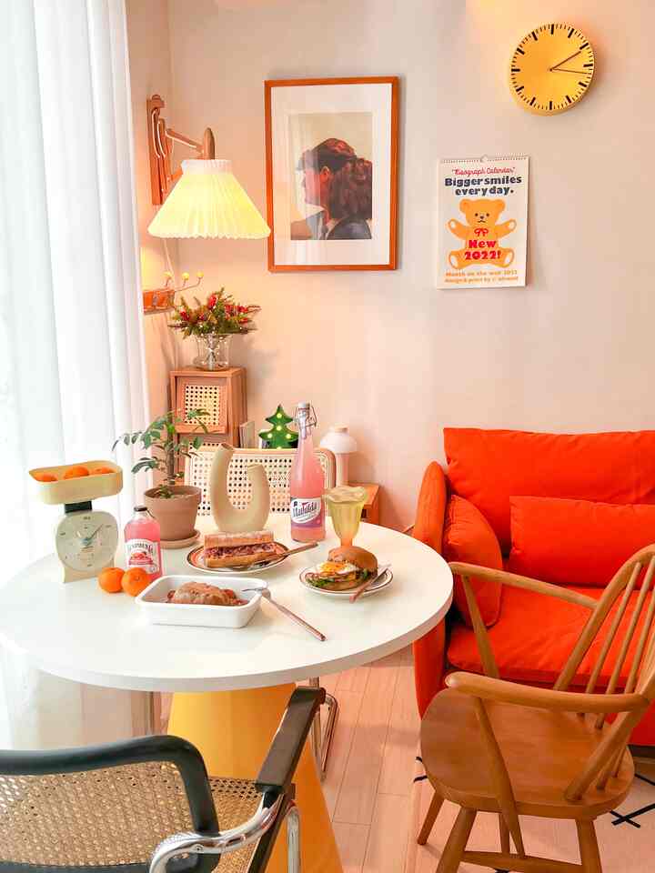 Warm orange and yellow toned living room featuring a round table and cozy sofa with natural wooden chairs creating a inviting atmosphere