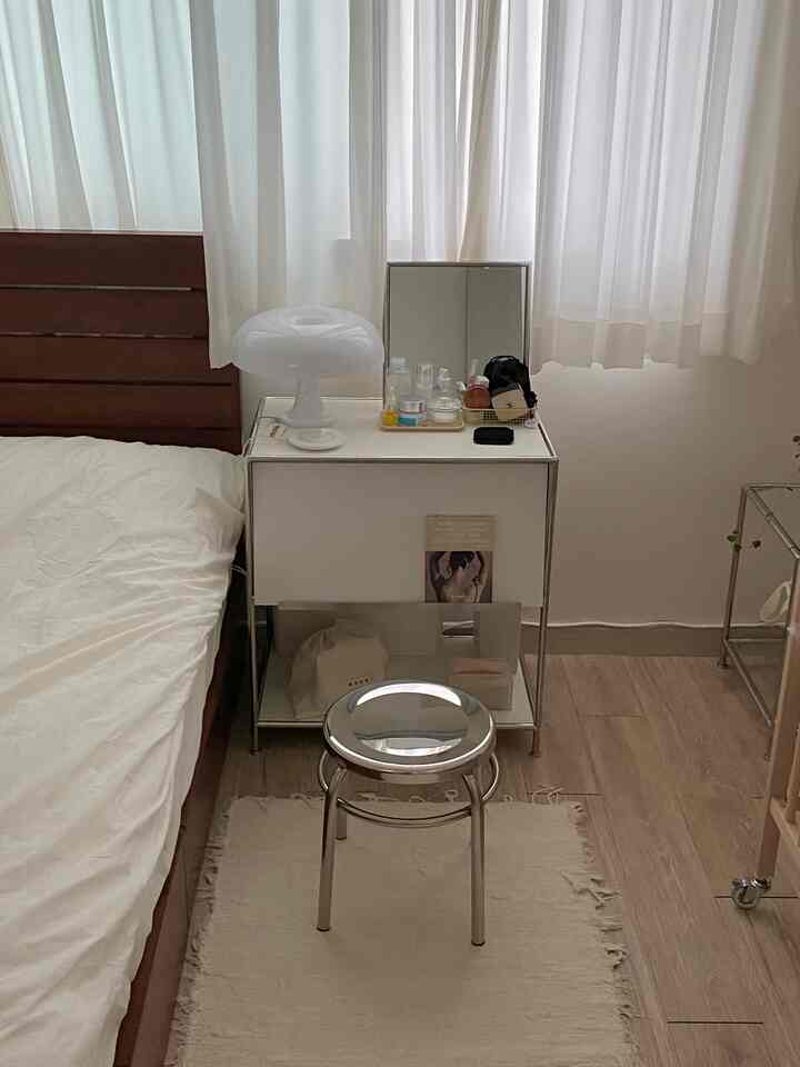 White and brown toned bedroom featuring a multifunctional stainless steel magazine rack nightstand and stool, creating a cozy atmosphere