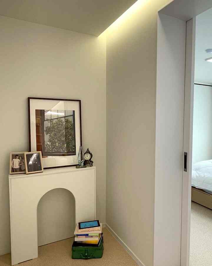 Ivory and beige toned hallway corner featuring a fireplace console and picture frames creating a calm natural space