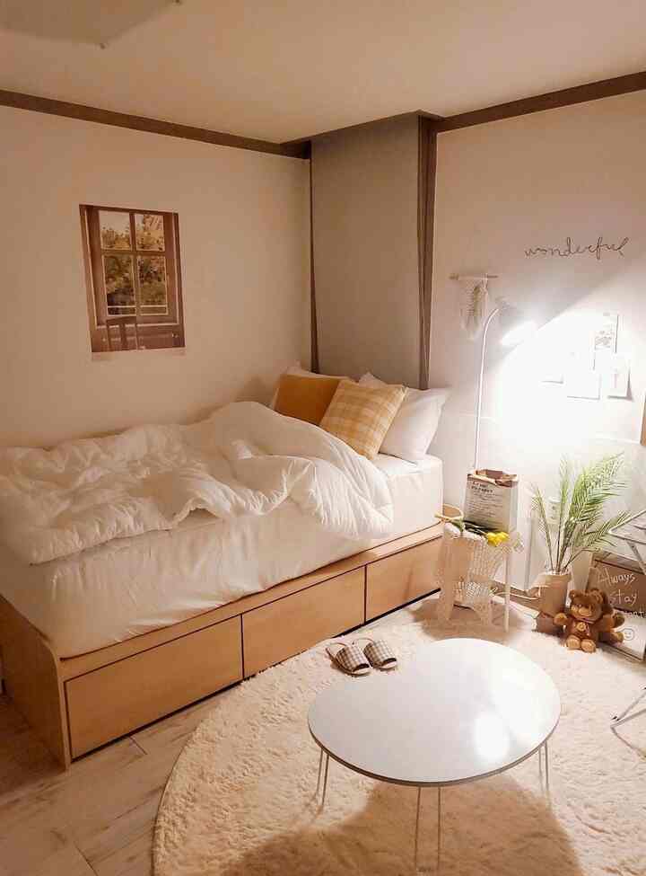 Small bedroom with warm yellow and natural tones featuring a storage bed, yellow cushions, and a floor lamp creating a cozy atmosphere