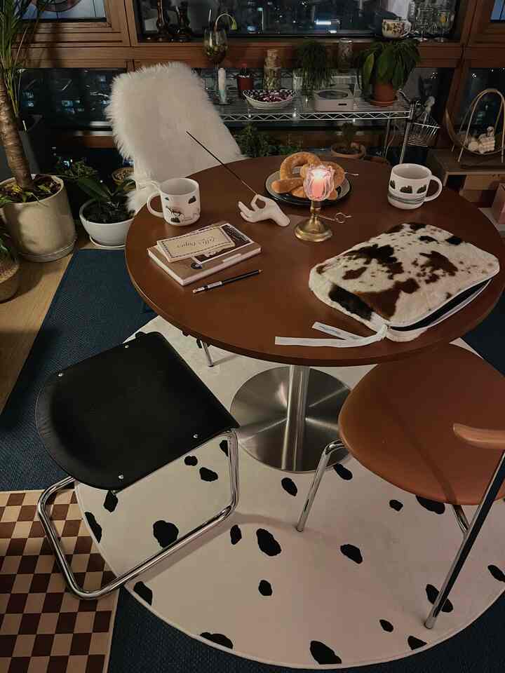 Wood-toned two-person dining room featuring a round table and rug, with a cozy home cafe atmosphere