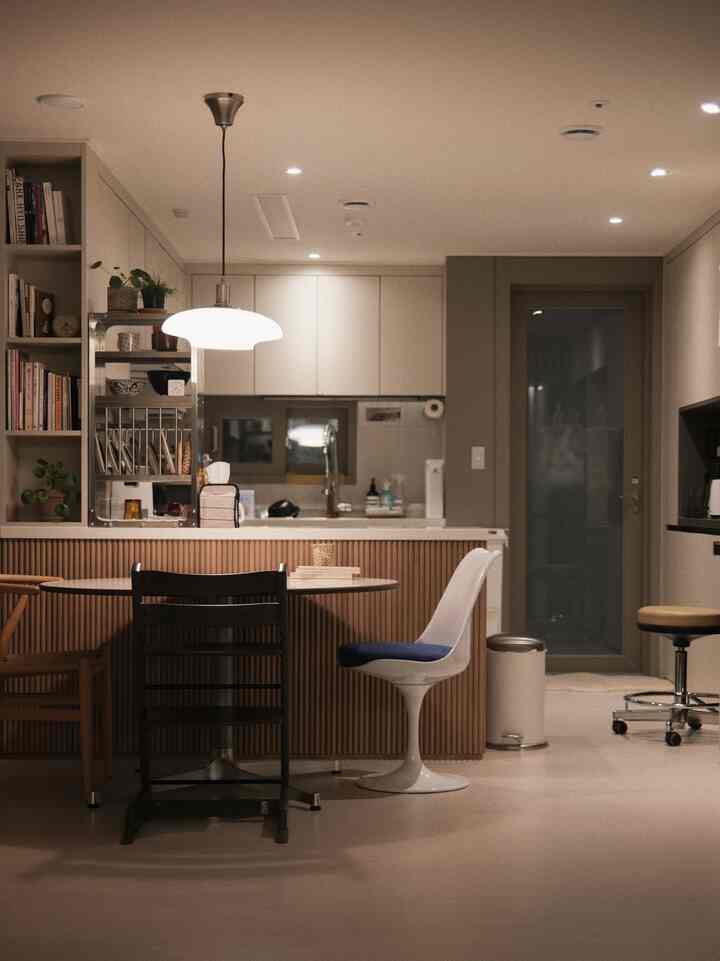 Modern dining room in warm white and wood tones, featuring a round dining table and diverse chairs creating a clean and cozy space
