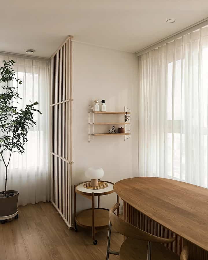 ナチュラルな木目調とホワイトの色調のダイニング、ベージュのシフォンカーテンと木製のダイニングテーブルが配置された落ち着いた雰囲気のインテリア