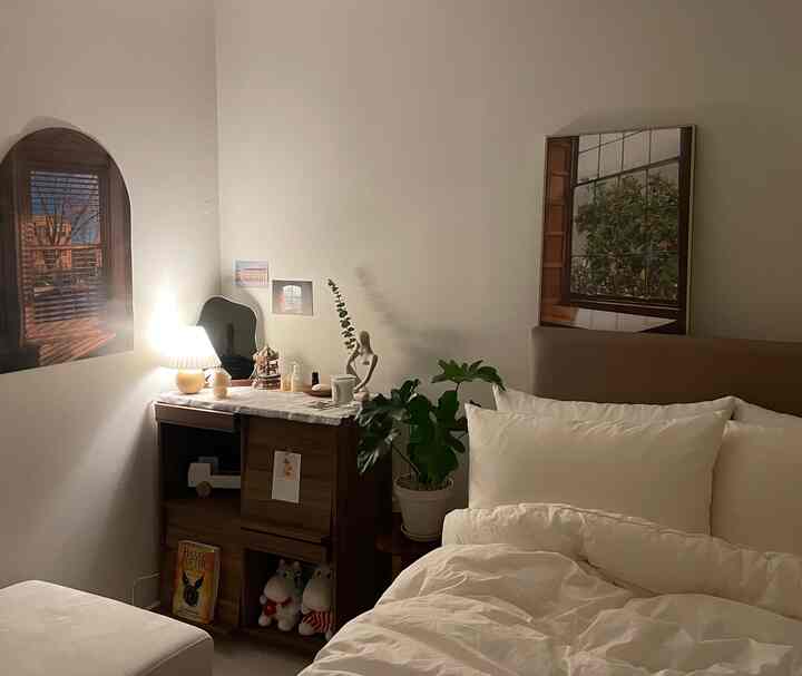 ホワイトとブラウンの色調の寝室、ベッドと木製家具、植物、暖かい間接照明が配置された雰囲気のあるインテリア