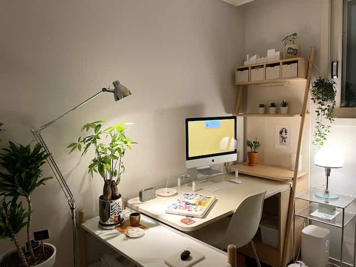 ベージュと木目調のモダンなホームオフィス、デスクとコンピューター、複数の植物が配置された雰囲気のあるワークスペース