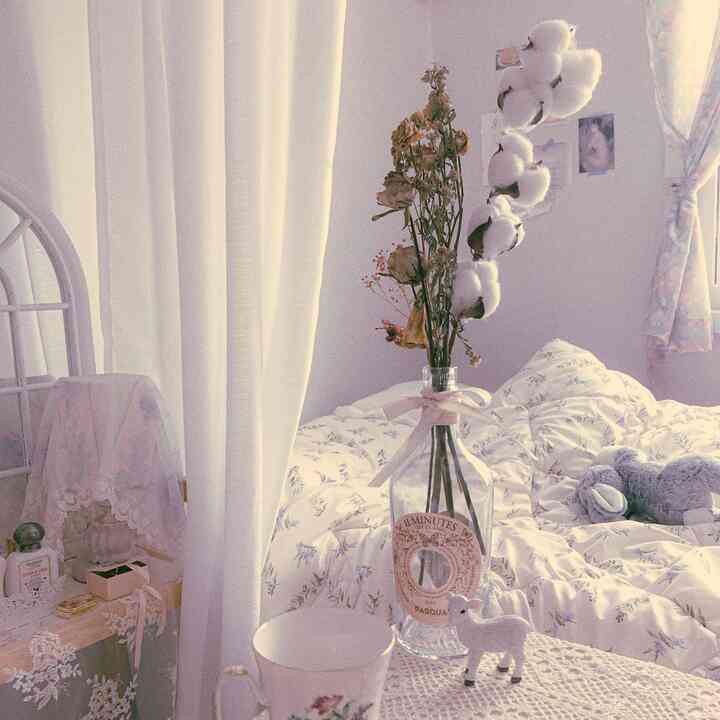 ホワイトとナチュラルトーンのワンルーム寝室、花瓶と繊細な寝具が調和したヴィンテージ感のあるインテリア