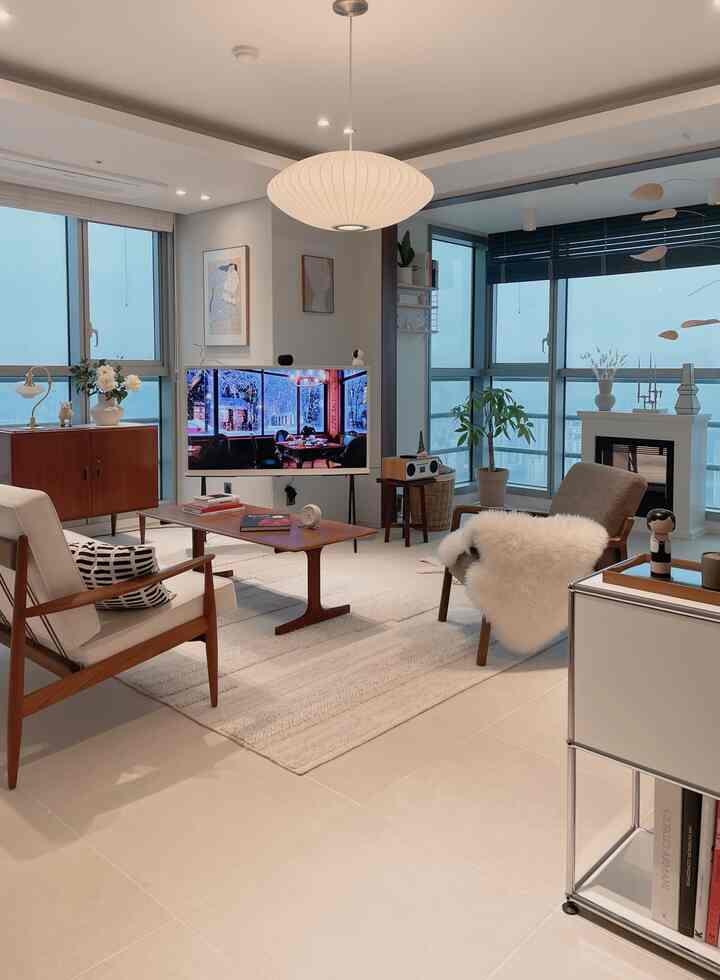Bright white and wood tone natural modern living room featuring sofas, coffee table, and pendant light with cozy and clean atmosphere