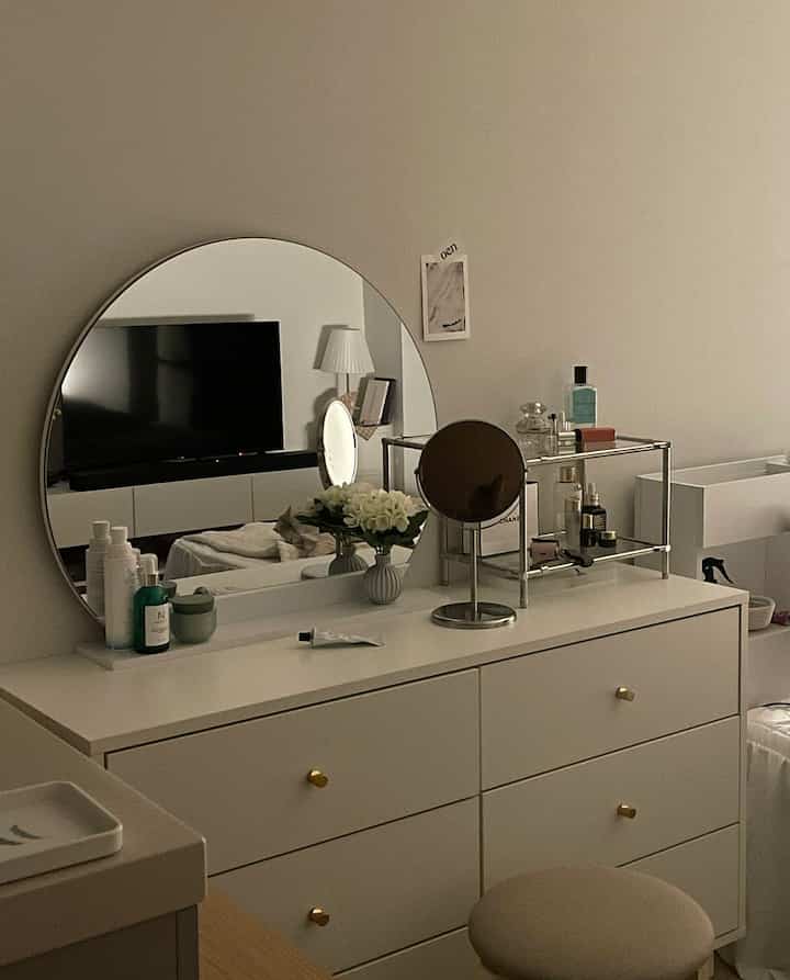 White-toned small room with vanity dresser and round mirror, styled simply and minimally