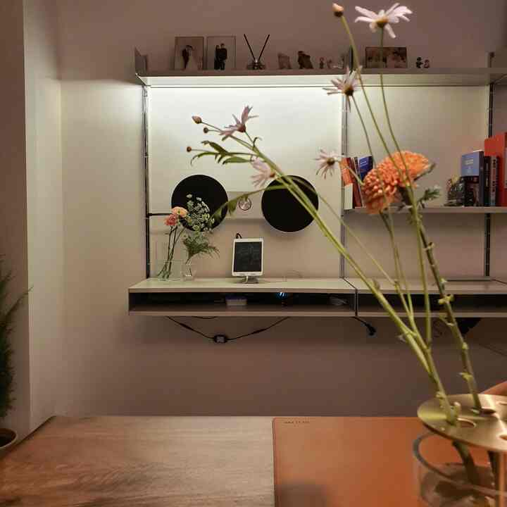 白と木目調のリビング、花瓶と花が配置されたシンプルで清潔感のある空間