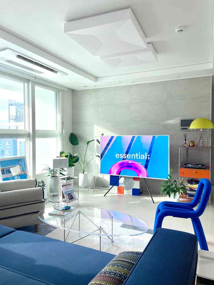 Bright living room in white and blue tones featuring a blue sofa and unique TV stand with a modern atmosphere