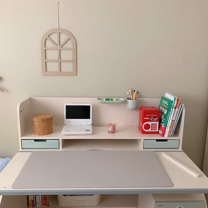 Natural beige-toned kids' room desk with monitor stand and neatly organized items, creating a tidy study space