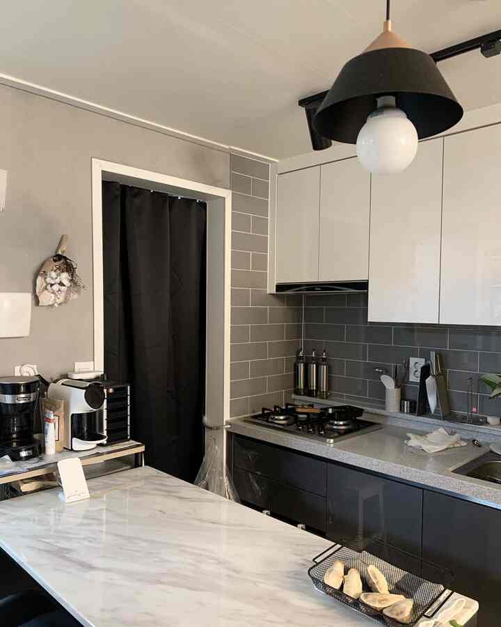 グレーと黒を基調としたキッチン、モダンな雰囲気の大理石のダイニングテーブルとコーヒーマシンが配置されたインテリア