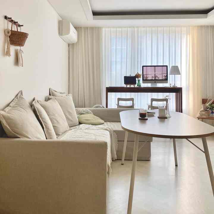White and beige toned living room featuring beige sofa and oval table in a natural modern style