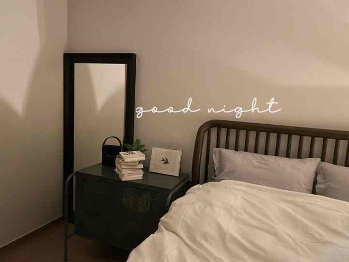 白と黒の調和がある寝室、木製ベッドと金属製のチェストが快適な雰囲気を演出している