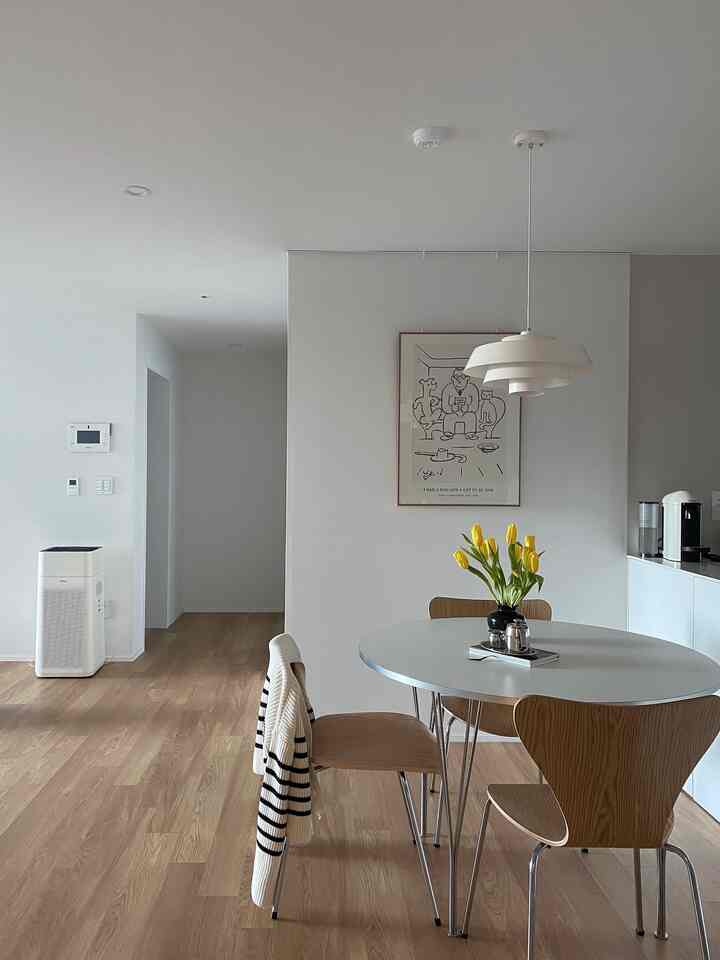White-toned dining room with wood flooring, featuring a round dining table and pendant light creating a cozy atmosphere