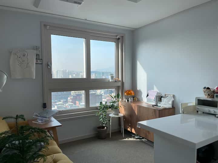 明るいナチュラルカラーの1.5ルームオフィステル、黄色のソファとホームオフィスが配置された空間