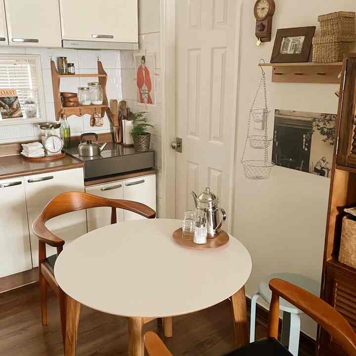Natural wood tones and white kitchen space featuring a round dining table and wooden chairs with a cozy atmosphere