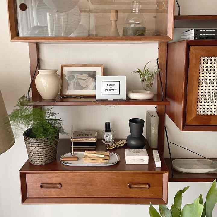 A natural-toned interior space with warm brown wall shelves featuring objets and plants