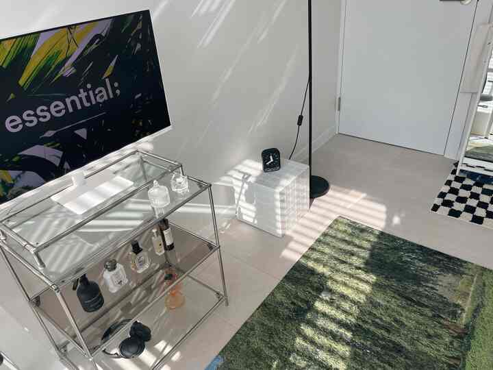 A white and green-toned living room featuring a metal shelf and practical side table in a clean, bright space
