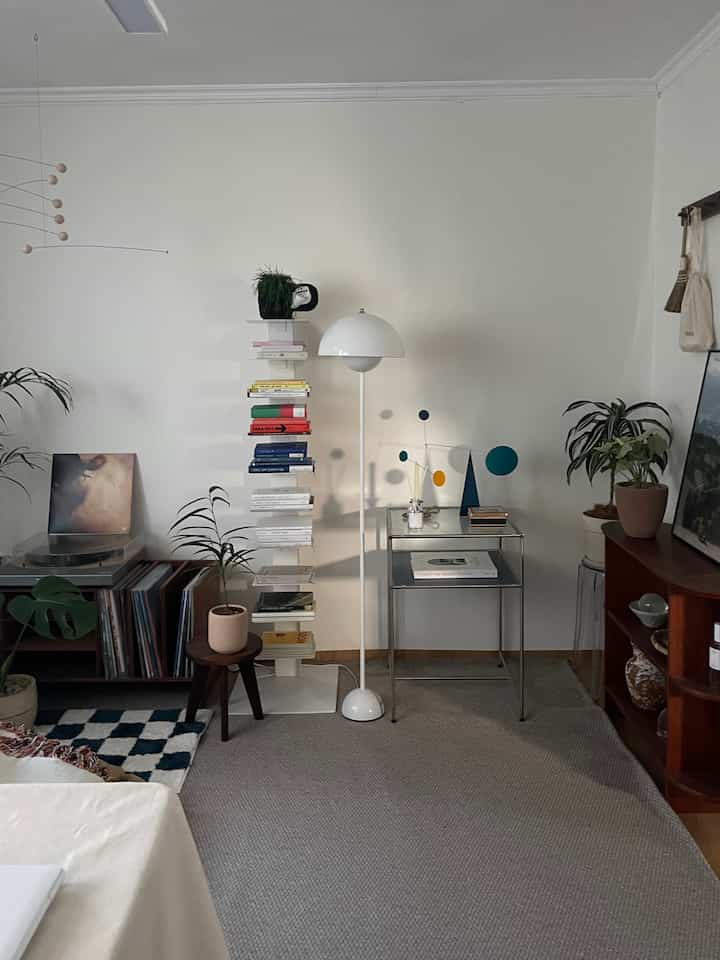 白と木目調が調和する北欧風リビング、フロアランプと本棚、モビールが配置されたシンプルな空間