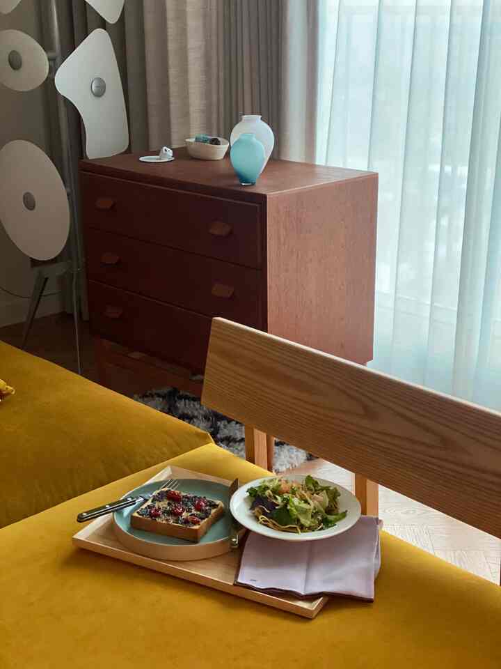 Yellow butternut fabric sofa and wooden storage cabinet in a tidy living room with window and sheer curtains