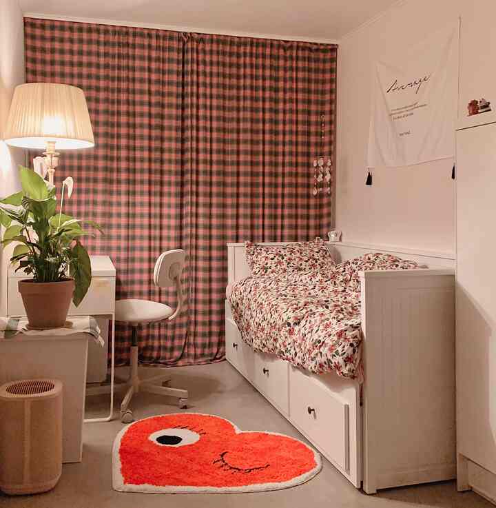 Cozy single-bedroom featuring warm brown plaid curtains and floral-patterned bedding, accented with minimal furniture and a floor lamp