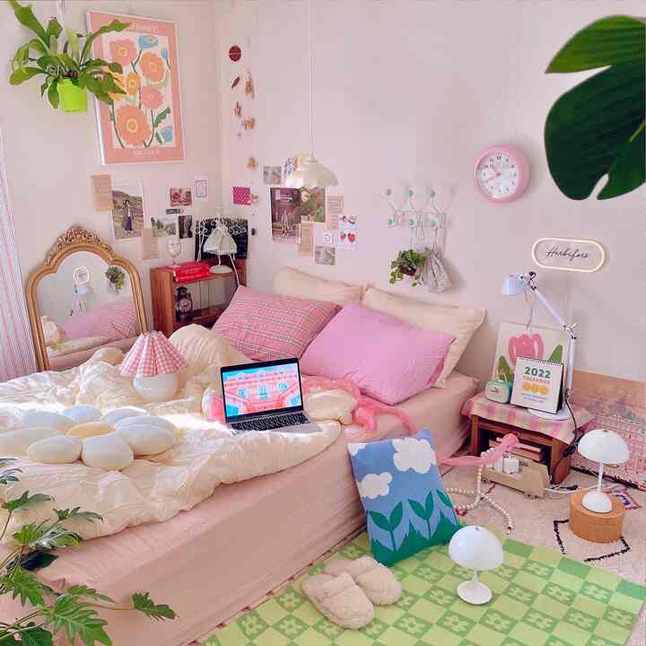 Pink and white toned bedroom featuring a bed with pink pillows and bedding, cozy with plants decorating the space