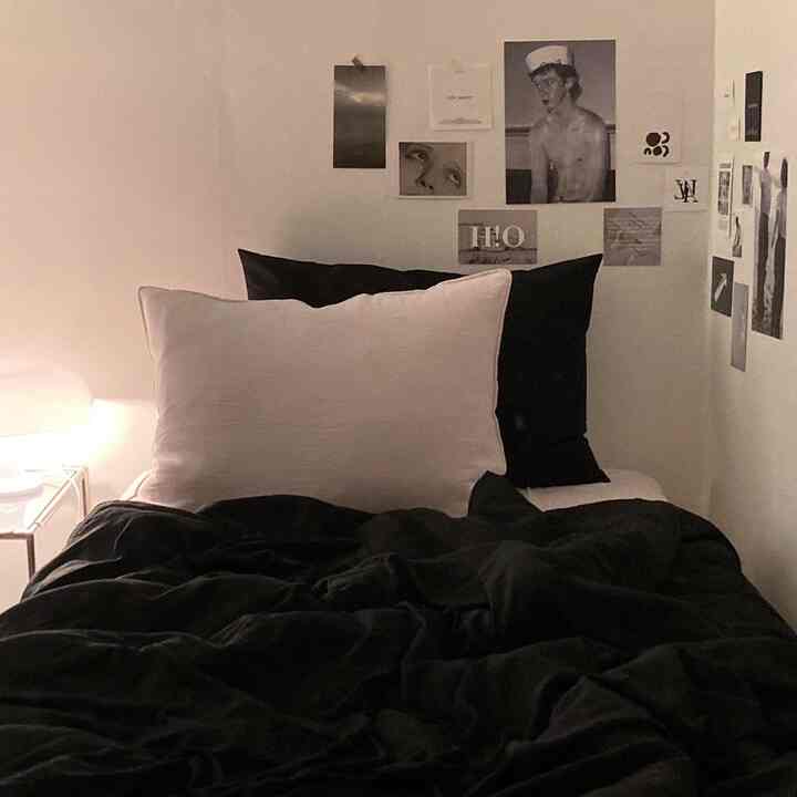 Black and white toned bedroom featuring simple bedding and pillows in a clean, minimalist space