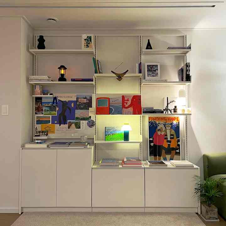 White tone study room featuring art books, picture frames, and posters arranged neatly in a modern and natural interior