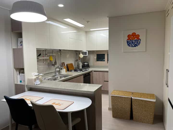 白と木目調が調和するキッチン、ダイニングチェアと実用的な調理器具が配置された印象的な空間