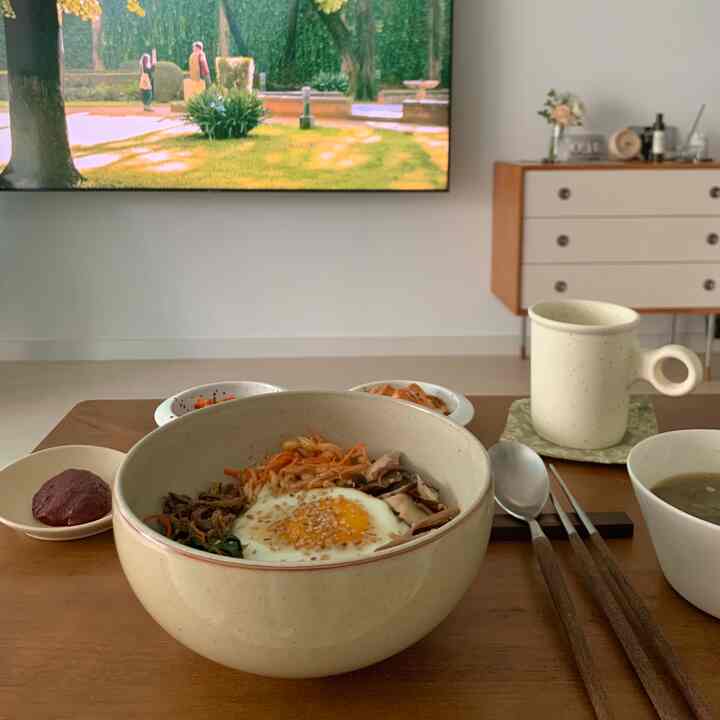 Natural beige-toned kitchen dining table featuring a bowl, cup, and cutlery for a cozy meal setting
