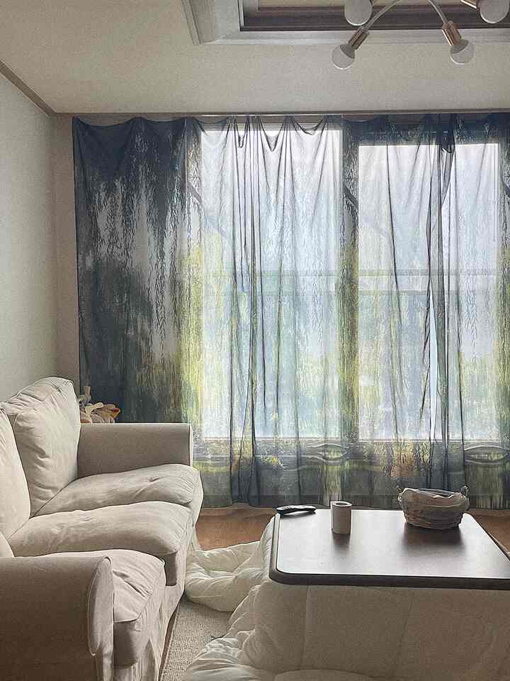 White and brown toned living room featuring soft sofa and kotatsu table with blanket, creating a cozy atmosphere