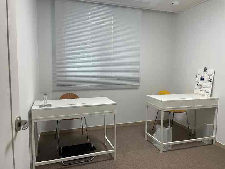 白を基調とした二人用書斎、シンプルなデスクと椅子が配置された落ち着いた作業空間
