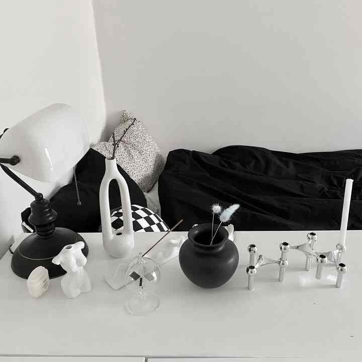 Monotone bedroom featuring black and white objet decor and a table lamp, in a simple neutral interior space