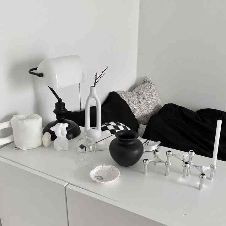 モノトーンのリビング、白いキャビネットの上にモダンな花瓶やランプが配置され、落ち着いた雰囲気のインテリア