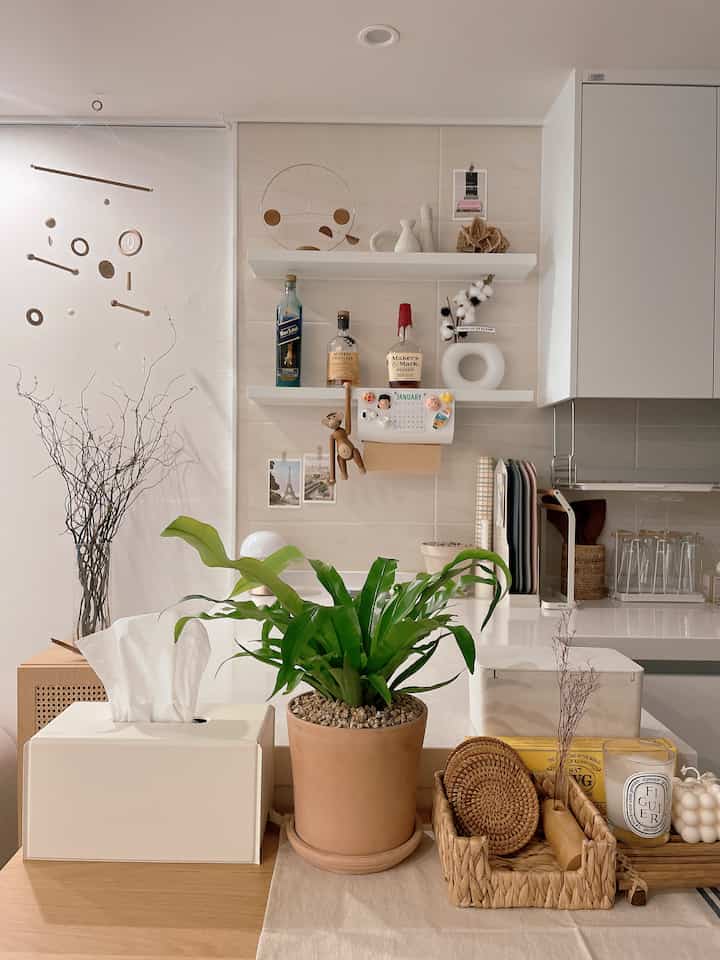 Beige-tone walls and natural wood table featuring plants and rattan accessories create a cozy kitchen area