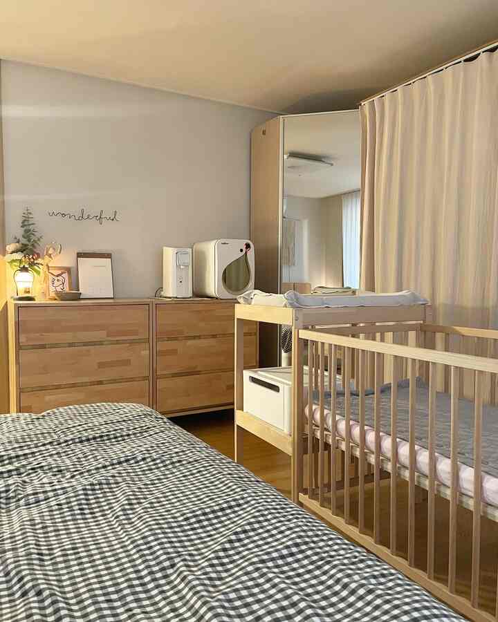 Natural wood tone and beige bedroom featuring a crib and changing table arranged for optimal baby care