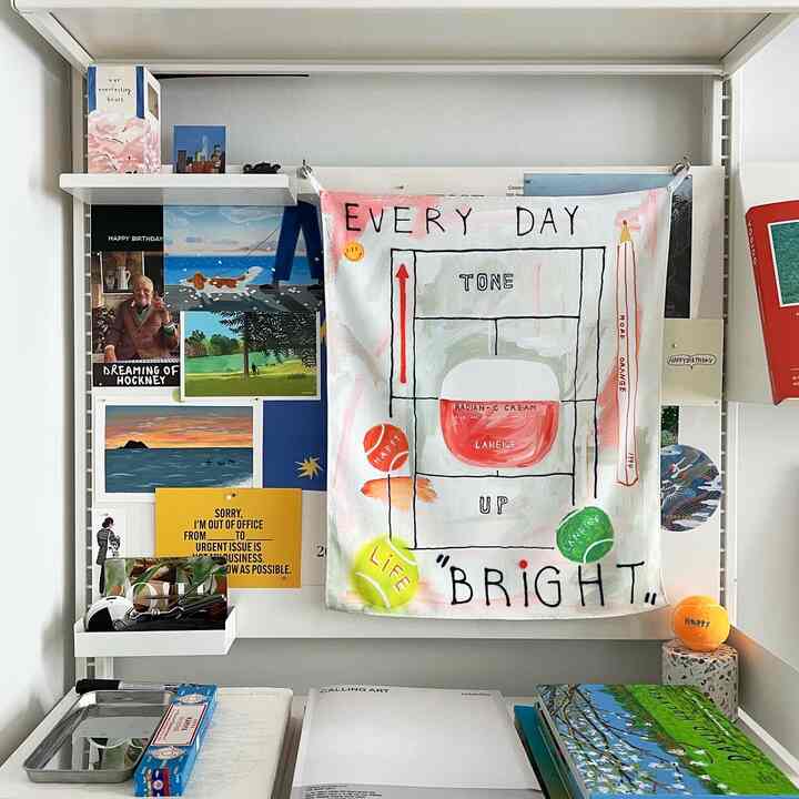 Bright artistic space with white system shelves, various posters, and tennis ball objets creating yellow accents