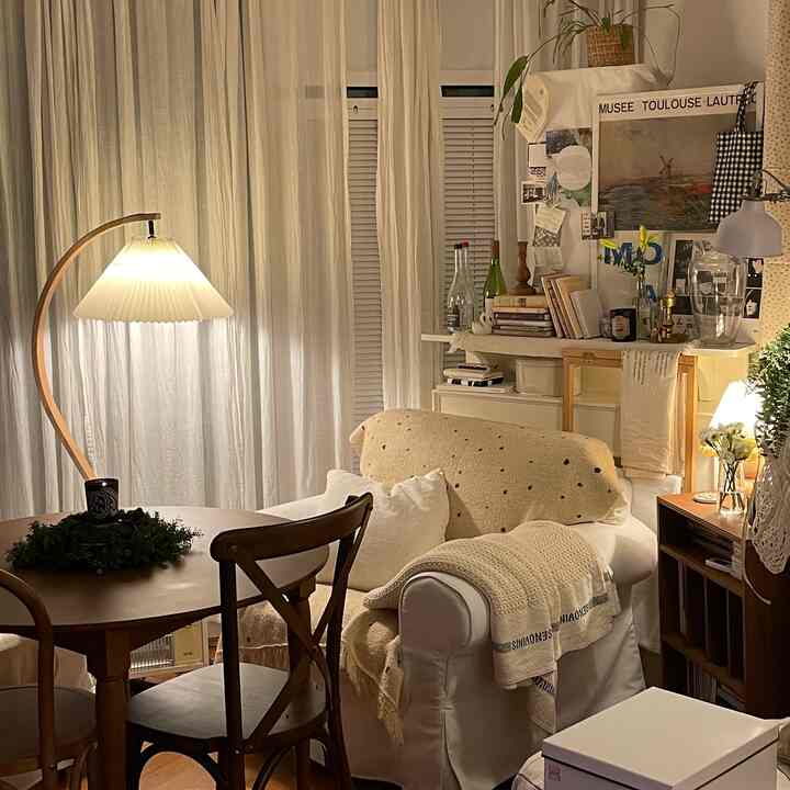 Beige and natural toned living room featuring a round dining table and bright floor lamp with cozy atmosphere
