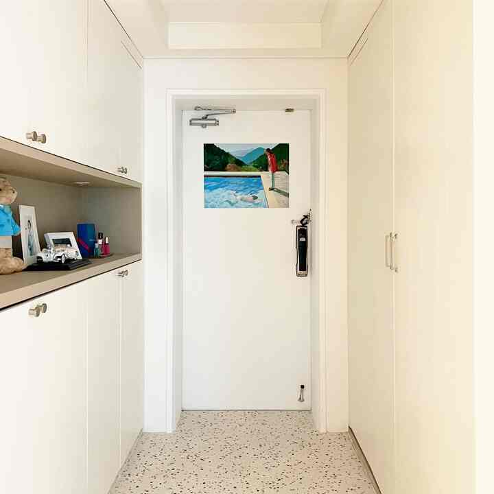 White-toned entrance featuring shoe cabinets on both sides and a vibrant art poster centered on the door, creating a clean and bright space