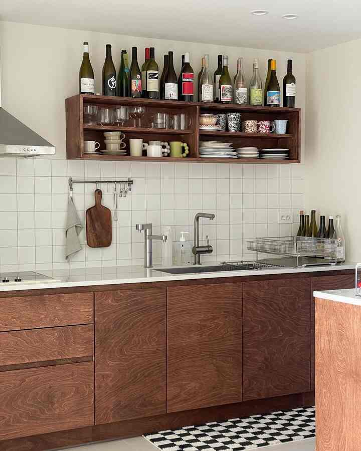 Modern wood-tone kitchen featuring white tiled backsplash, open wooden shelves, and lower wood cabinetry