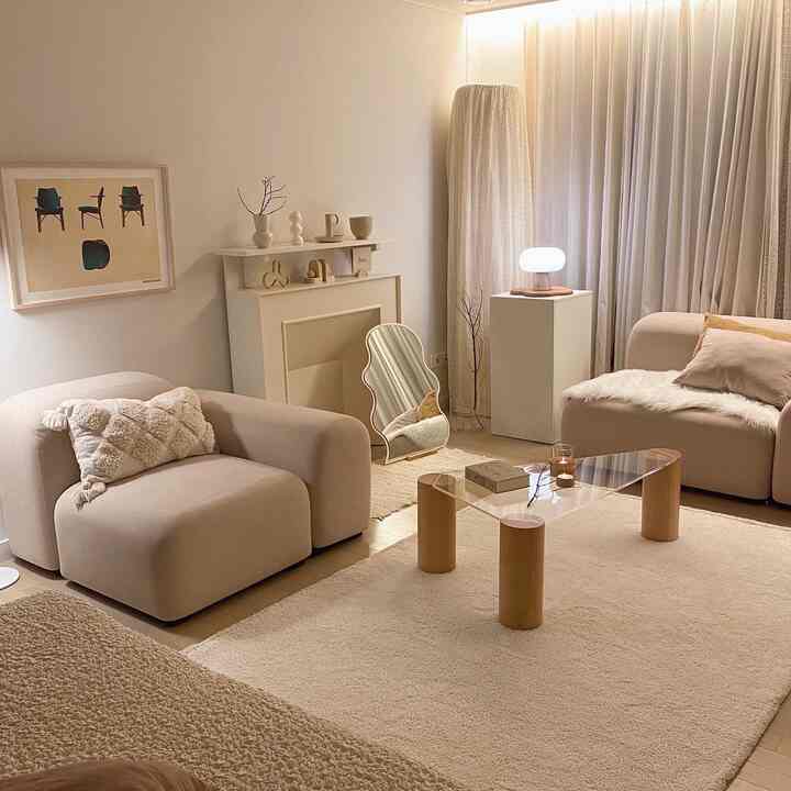 Soft beige and white toned living room featuring two sofas, a glass coffee table, and a floor lamp creating a cozy atmosphere