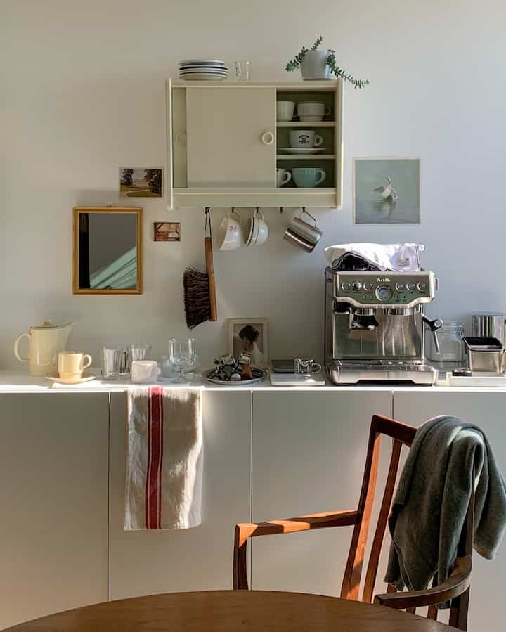 White and brown toned kitchen space featuring coffee machine and tableware, creating a cozy home cafe atmosphere