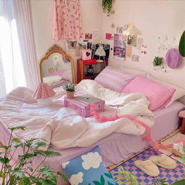 Pink and white toned bedroom featuring a single bed with bedding, plants, and various decorative items creating a cozy space
