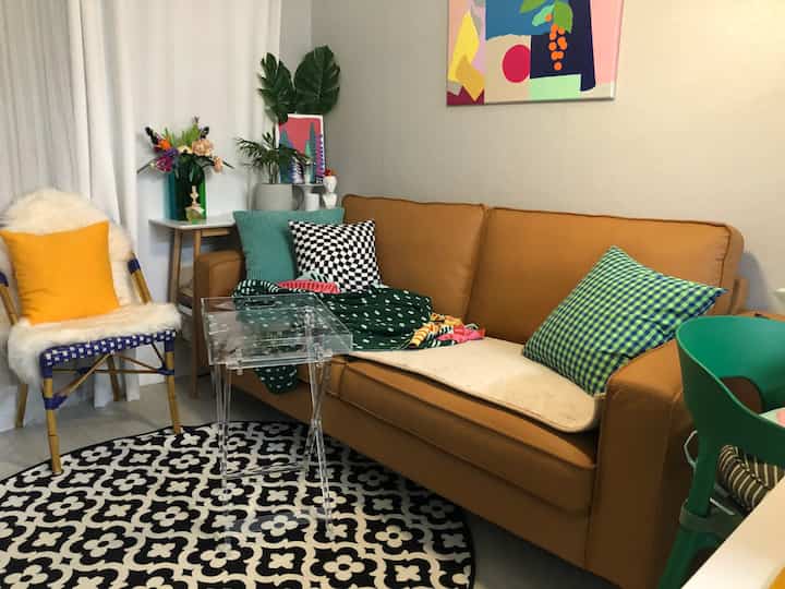 Warm natural color living room featuring brown sofa, assorted cushions, and round patterned rug creating a cozy atmosphere