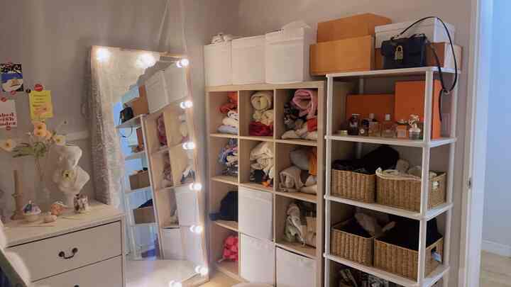 Natural toned walk-in closet with white storage boxes and large mirror in a tidy space