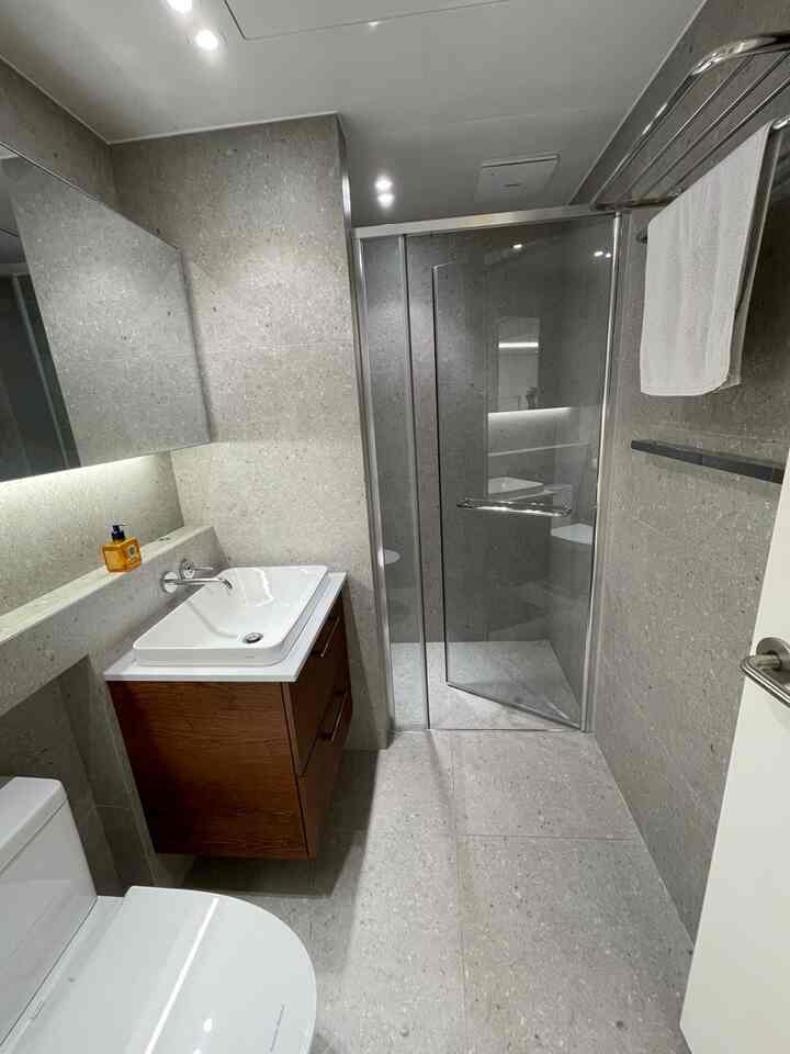 Gray and white toned bathroom featuring a brown wooden cabinet and two towel racks with a clean modern design