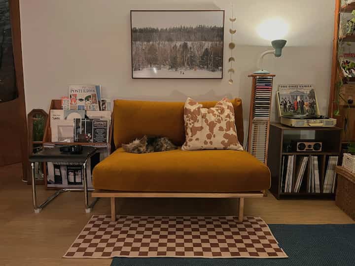 Warm yellow sofa-centered living room featuring wall art and a turntable creating a cozy atmosphere